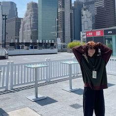 a woman standing in front of a cityscape with her hands on her head