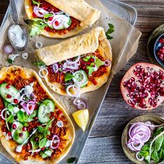 three pita breads with various toppings on top of them, next to a bowl of salad