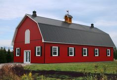 a red barn with white windows and a black roof