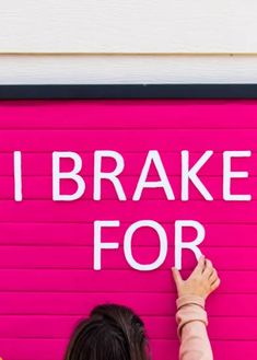 a woman standing in front of a pink garage door with the words i brake for written on it