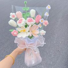 a person is holding a bouquet of flowers in their hand on the street with someone's hand