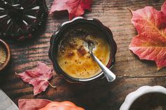 an overhead view of a cup of coffee on a table with autumn leaves