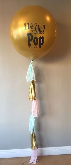 a gold balloon with tassels hanging from it's side on the wall