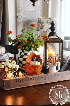 a wooden tray with candles, flowers and other decorative items on it in front of a window