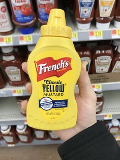 a person holding up a bottle of mustard