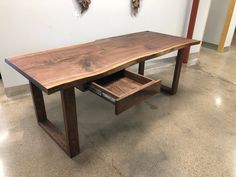 a wooden table with two open drawers on the bottom and one closed drawer underneath it