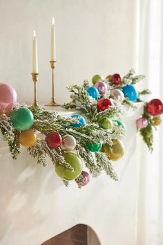 a mantle decorated with christmas ornaments and candles