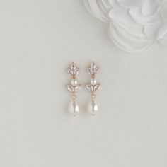 two pairs of pearl and crystal earrings on top of a white flower headband,