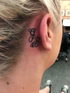 a woman with a tattoo behind her ear that has the letters b and c on it