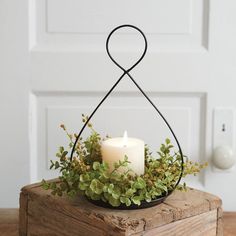 a candle that is sitting on top of a wooden box with some plants in it