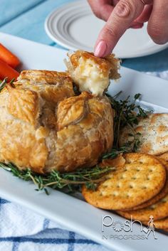 a person is picking up some food from a plate with crackers and carrots