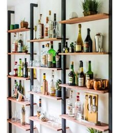 shelves filled with bottles and glasses on top of wooden shelves next to a white wall