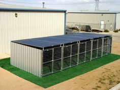 a large metal structure sitting on top of a grass covered field next to two buildings