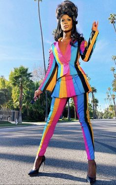 a woman is standing in the middle of the street wearing a colorful suit and heels