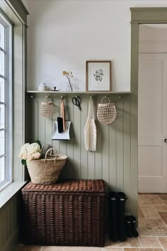 a basket is sitting on top of a bench in front of a wall with hooks