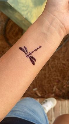 a woman's arm with a tattoo that has a dragonfly on the wrist