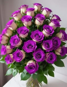 a vase filled with purple roses on top of a table