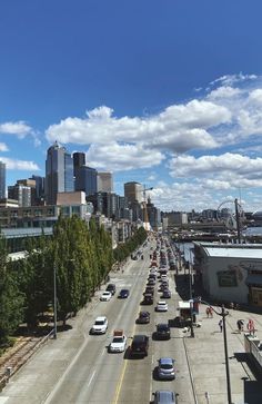 cars are driving down an empty street in front of the city skyline with tall buildings