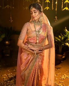 a woman in an orange and pink sari with gold jewelry on her neckline