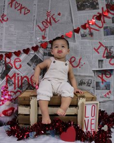 a baby sitting on top of a wooden crate surrounded by valentine's day decorations