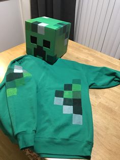 a green shirt with an image of a creeper on it sitting on top of a wooden table