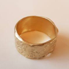 Organic form meets expert craftsmanship with this stunning solid 18K gold women's wedding band. A subtle yet sensational statement, this piece has an apparent weight and impressive width with naturally undulating sides and a rough-textured surface. Each ring is handcrafted and one of kind just like the singular union they represent. ◈ DETAILS Weight: 6g Width: 12-13mm / 0.47''- 0.51'' Thickness: 1.1-1.5mm / 0.39''- 0.06'' ◈ MATERIAL 18K Solid Gold ◈ ALSO AVAILABLE IN 14K Yellow, Rose, or White G Gold Hammered Wide Band Ring, Gold Hammered Thick Band Ring, Hammered Yellow Gold Wide Open Band Ring, Hammered Yellow Gold Wide Band Open Ring, Heirloom Hammered Rings In Recycled Gold, Heirloom Recycled Gold Hammered Rings, Gold Hammered Thick Band Jewelry, Gold Hammered Ring In Recycled Gold, Hammered Gold Ring In Recycled Gold