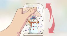 a snowman in a glass jar being held by someone's hand with an arrow pointing at it