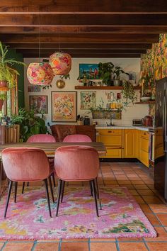 a kitchen with yellow cabinets, pink chairs and an area rug on the floor in front of it