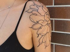 a woman's arm with a flower tattoo on the left side of her shoulder