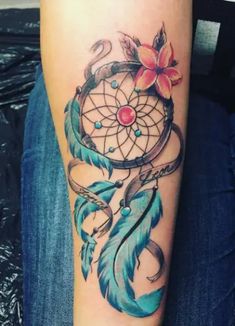 a woman's arm with a tattoo on it that has a dream catcher and flowers