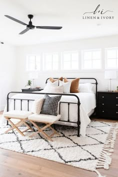 a bedroom with white walls and black furniture, including an iron bed frame that has pillows on it