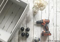 drillers, screwdrivers and other tools sitting on a white wooden floor next to a drawer