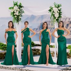 four women in green dresses standing next to each other with one woman wearing a high slited dress