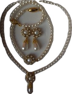 a necklace with pearls and charms on it's side, including a cross pendant