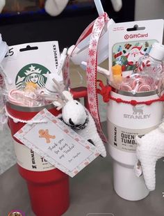 two starbucks coffee cups filled with candy and candies, one is wrapped in red ribbon and the other has a stuffed animal