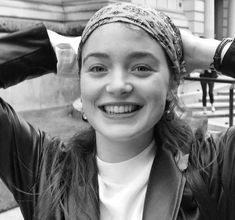 a woman is smiling and holding her hair in the air