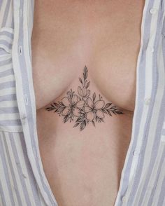 a woman's chest with flowers and leaves tattooed on the top of her breast