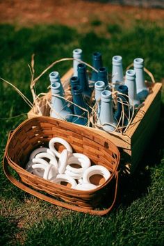 a basket filled with blue bottles sitting on top of a lush green field