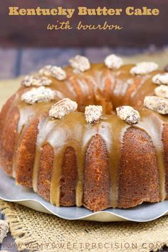 a bundt cake with icing and walnuts on top sitting on a plate