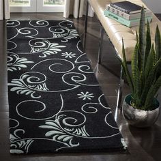 a black rug with white swirls on it in front of a couch and window