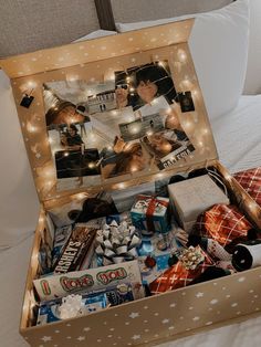 an open suitcase filled with various items on top of a bed next to a pillow