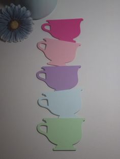 there are five cups on the wall with a flower in the corner next to it