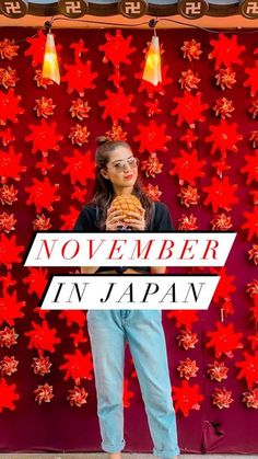 a woman standing in front of a red wall holding a doughnut with the words november in japan