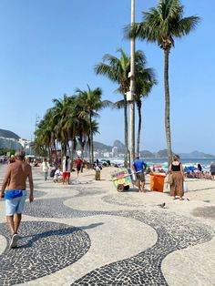 people are walking on the beach near palm trees