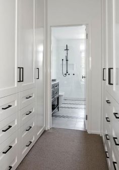 an empty hallway with white cabinets and black handles on the doors is seen in this image