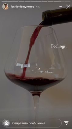 a wine glass filled with red wine being poured into it