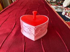 a heart shaped container sitting on top of a red table cloth