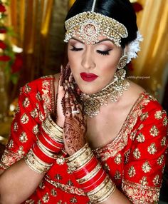 a woman wearing a red and gold bridal outfit holding her hands to her face