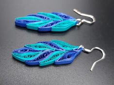 two pairs of blue and green earrings on a black surface