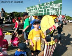 a group of people standing next to each other in front of a baseball field sign